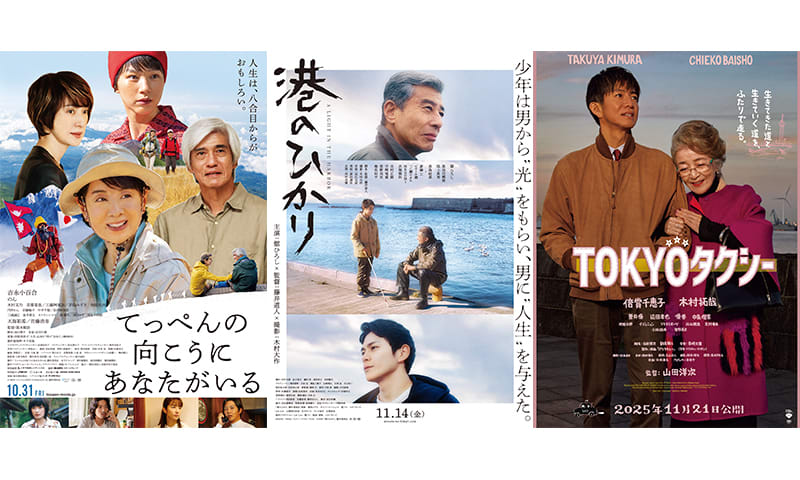 白いシャツを着た若手監督が、三脚の上の大きな映画カメラを覗き込む。新作映画の撮影現場での真剣な眼差しが印象的。
